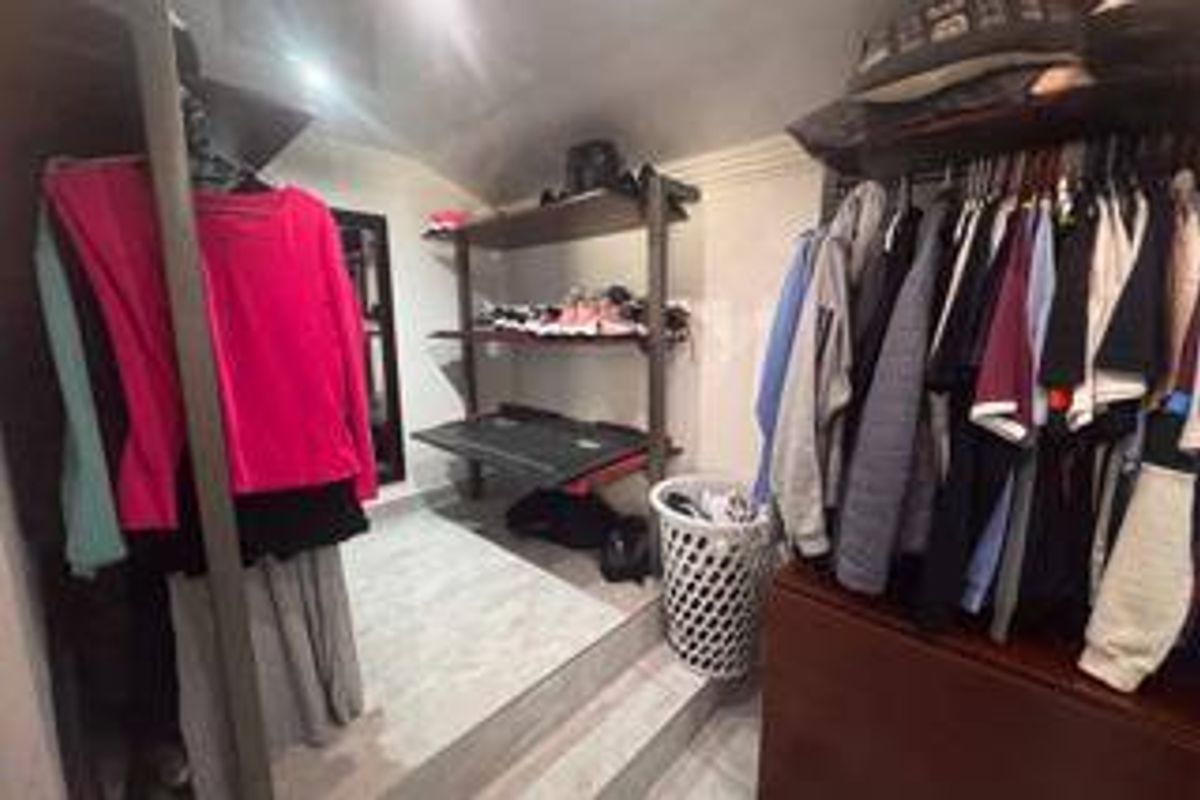 A walk-in closet or dressing area featuring built-in shelving units and tiled flooring, providing organized storage space.