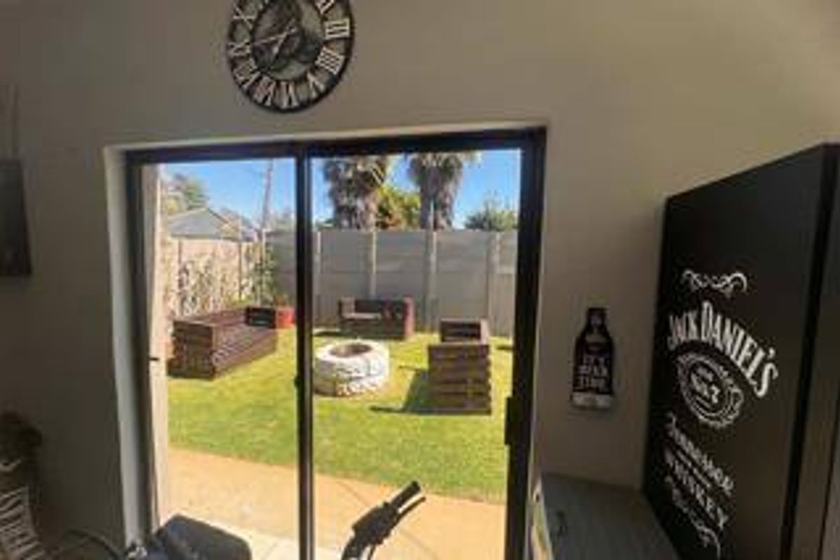 Interior living space featuring a large sliding glass door providing direct access to a private rear garden with a lawn and fire pit area.