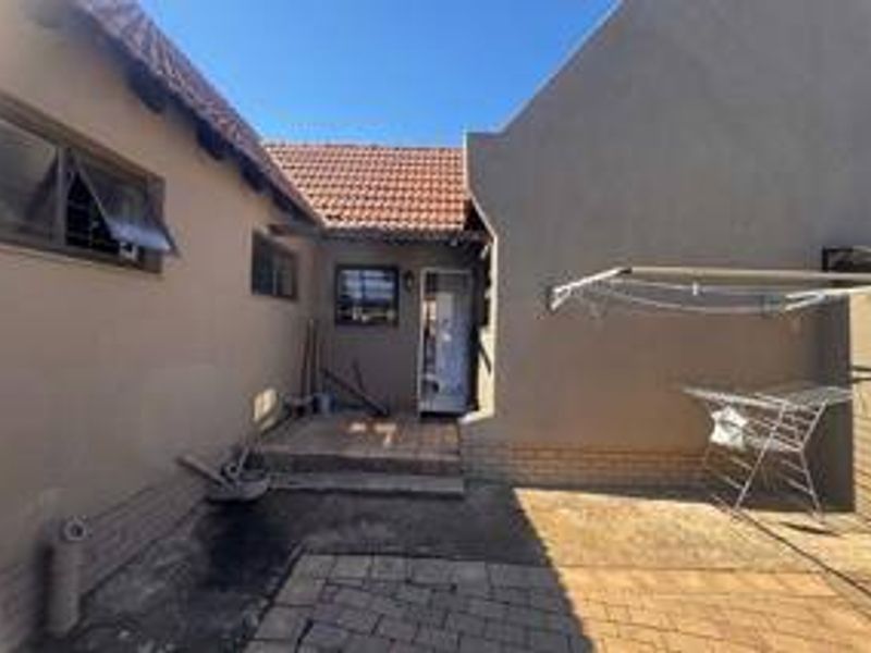 A rear courtyard area featuring paved flooring, brick walling, and access to the main dwelling via an external door.