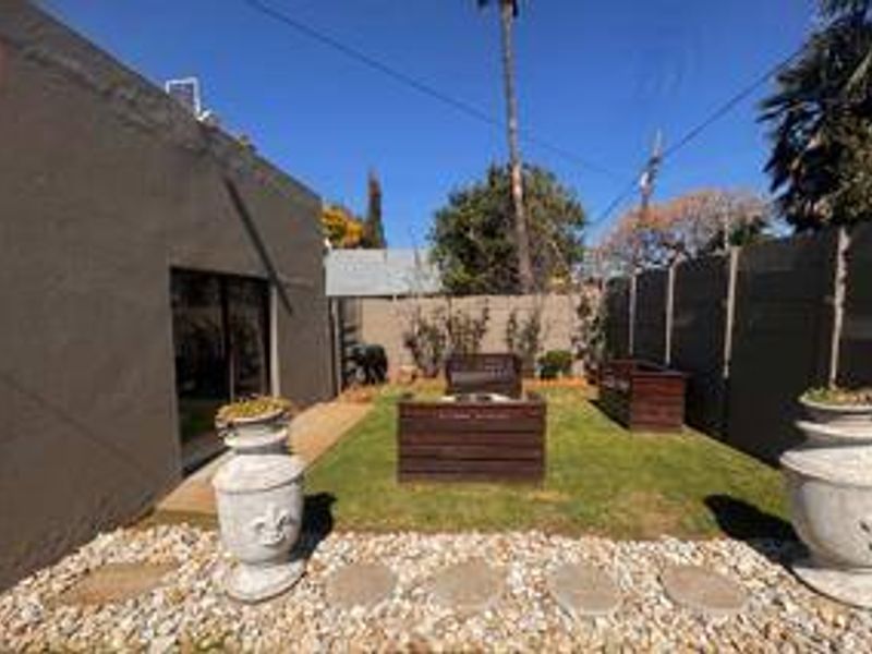 A private rear garden area featuring a small lawn, gravel pathway, and sliding door access to the main dwelling.