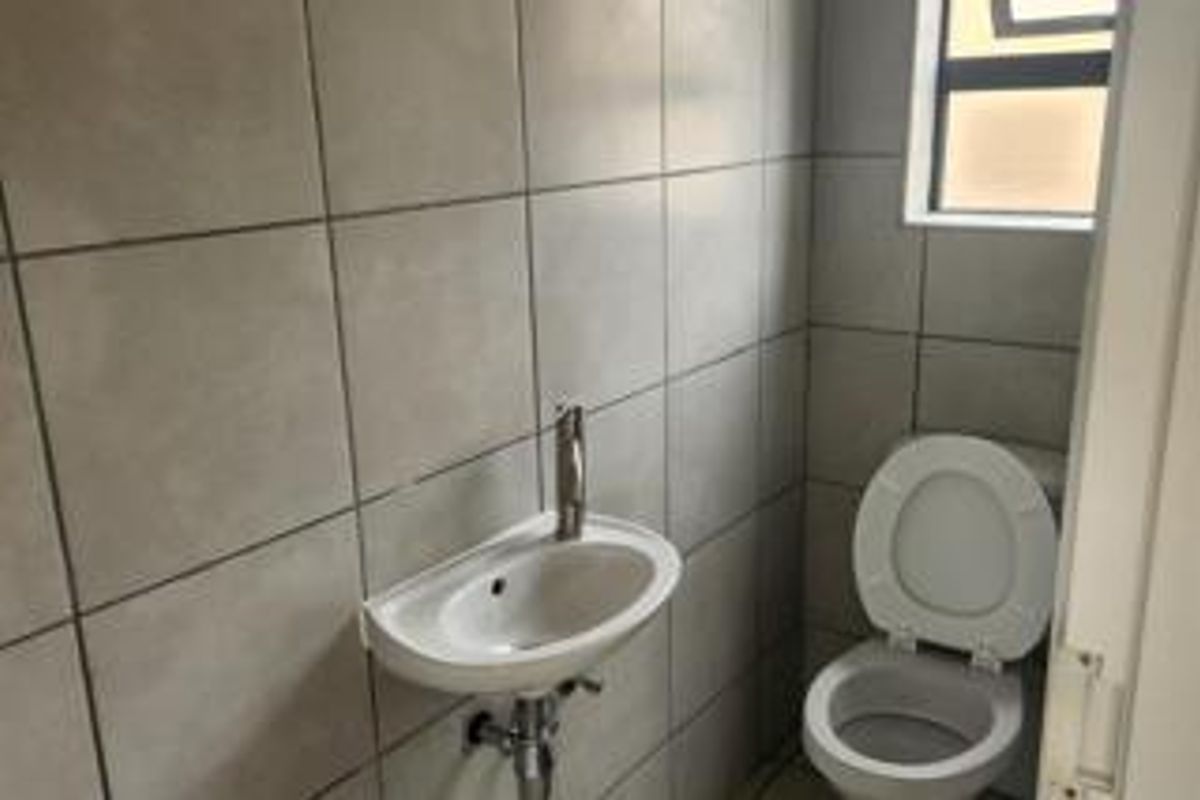 A compact guest bathroom featuring tiled walls, a wall-mounted basin, and a standard toilet.