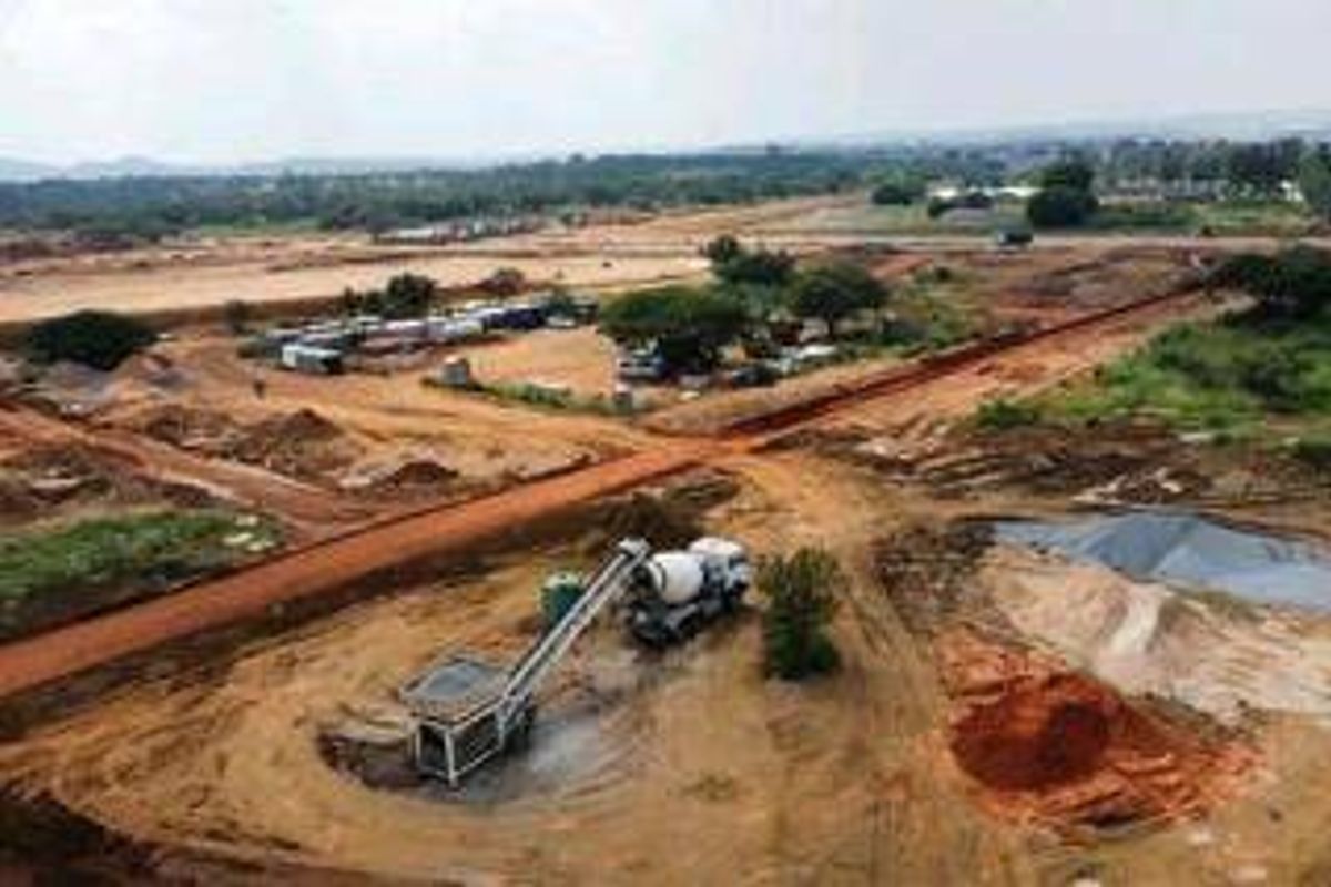 An aerial view of a large construction site or undeveloped land plot showing earthworks and heavy machinery.