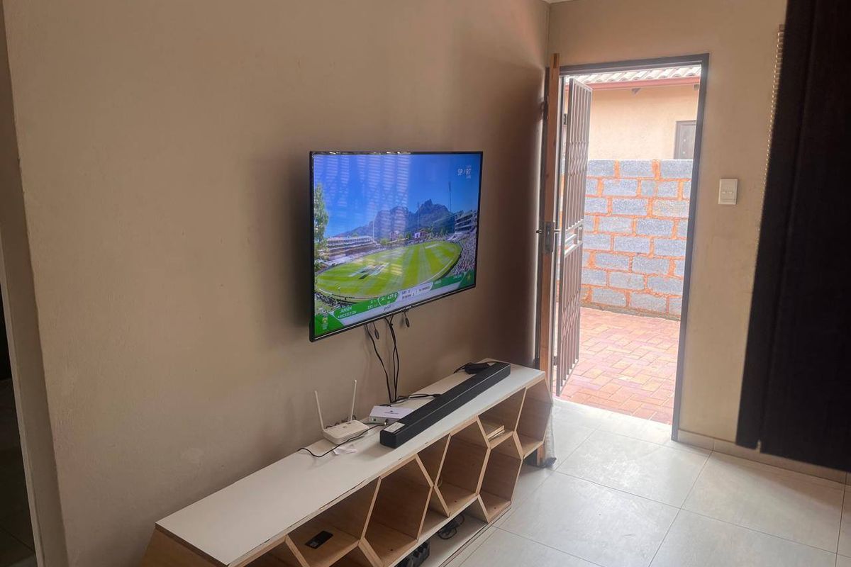 A living area featuring tiled flooring and direct access to an outdoor paved space through a security gate.