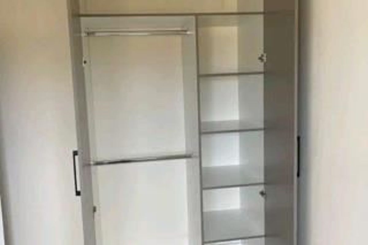 A clean, modern built-in wardrobe featuring integrated shelving and hanging rails for efficient bedroom storage.