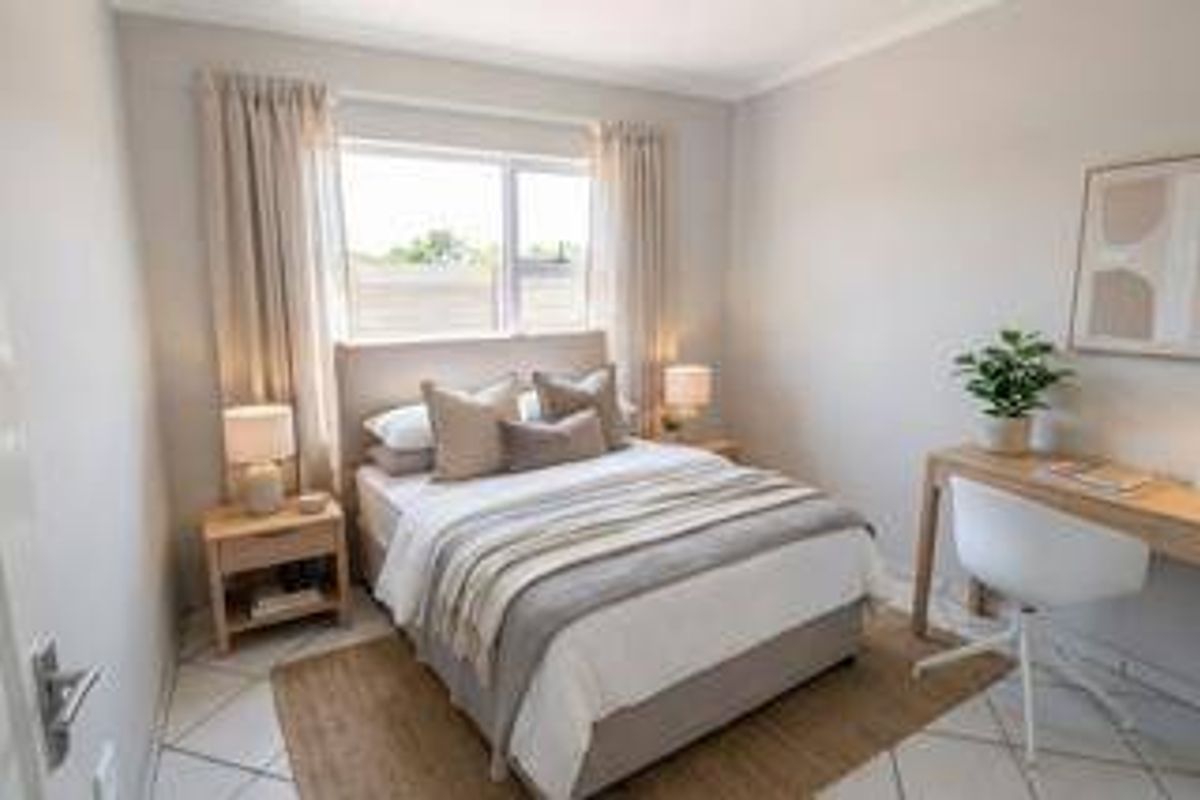 A well-maintained bedroom featuring neutral wall tones, tiled flooring, and a large window allowing for natural light.