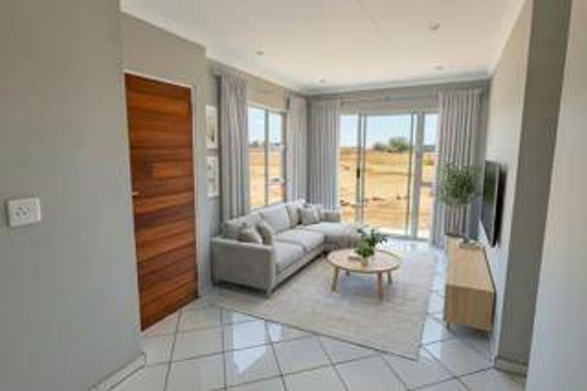 A bright and modern living room featuring tiled flooring, recessed lighting, and large sliding glass doors that provide natural light and outdoor access.