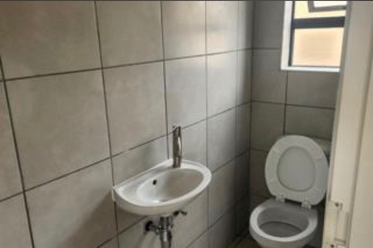 A compact guest bathroom featuring full-height wall tiling, a wall-mounted basin, and a standard toilet.