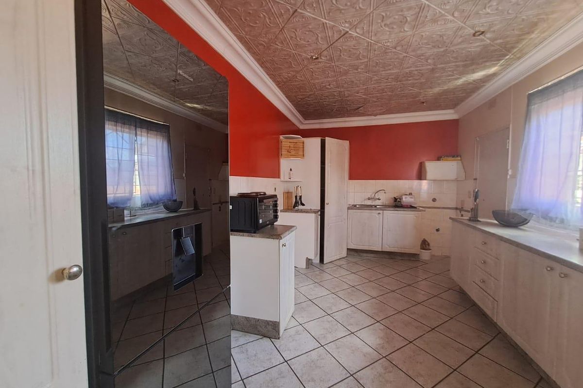 A spacious kitchen featuring tiled flooring, built-in cabinetry, and decorative ceiling tiles, offering significant potential for a modern renovation.