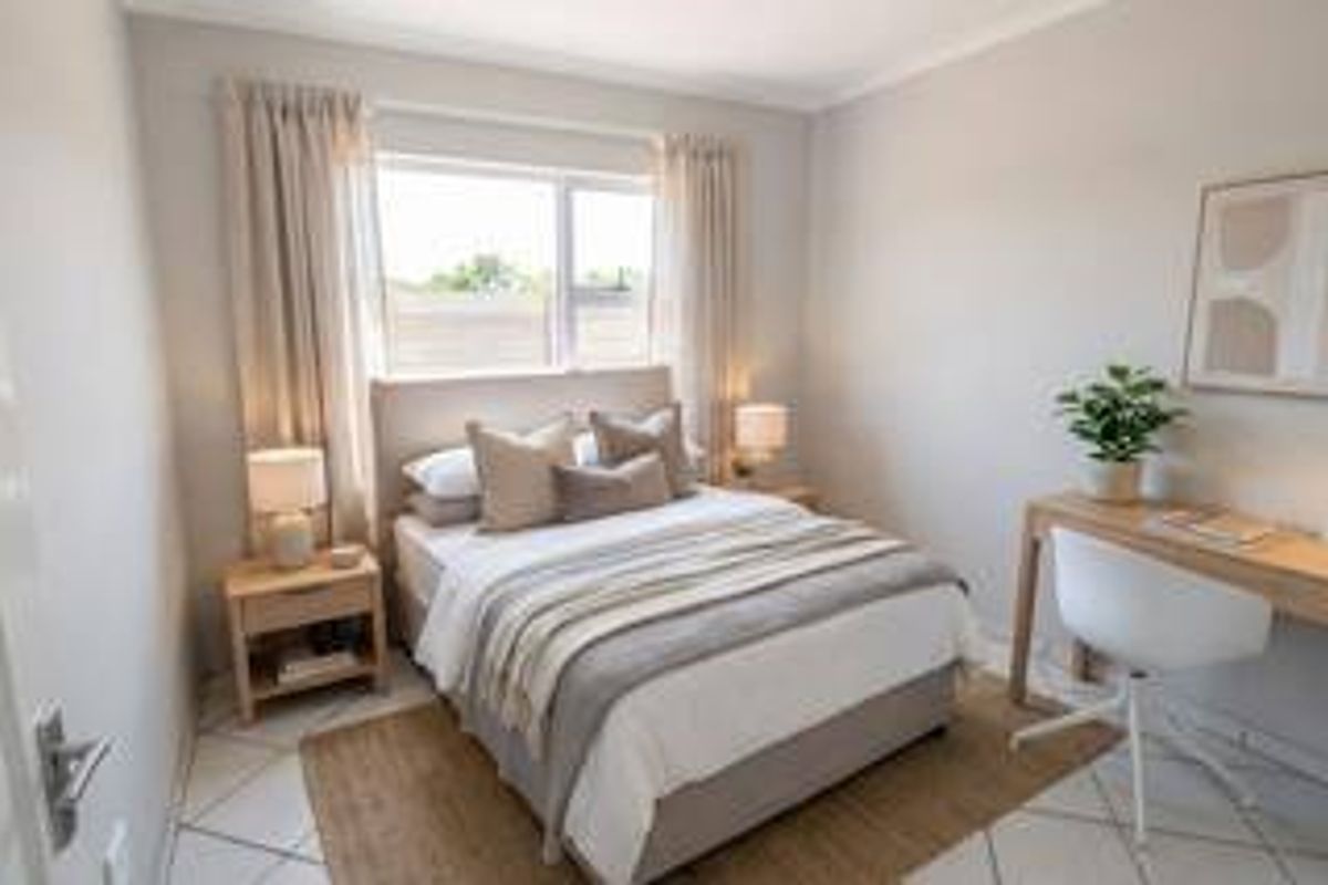 A well-lit, neutrally decorated bedroom featuring tiled flooring and a window, providing a comfortable and inviting living space.