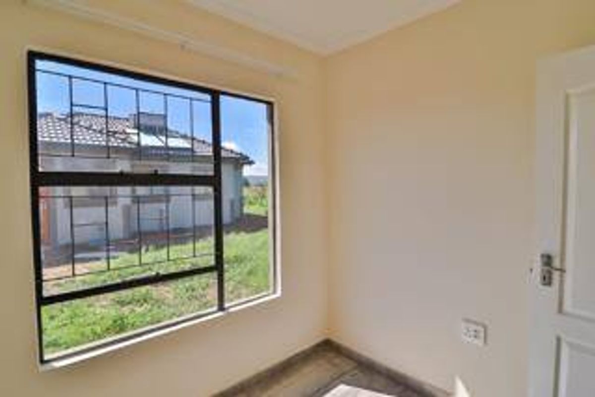 A bright, empty bedroom featuring security bars on the window and neutral wall finishes.