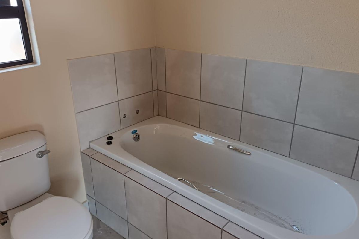 A clean, functional bathroom featuring a built-in bathtub with tiled surround and a standard toilet.