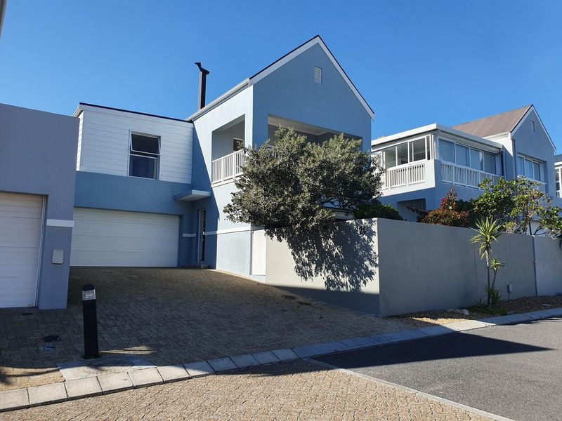 Front elevation of a modern townhouse featuring a paved driveway, single garage, and an upper-level balcony with a chimney.