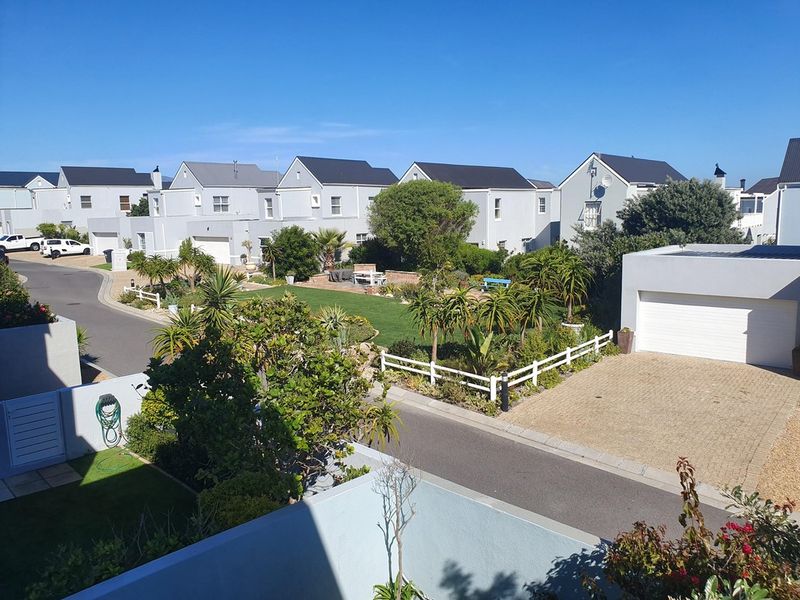 Elevated view of a residential townhouse complex featuring paved driveways, garages, and well-maintained communal garden areas.