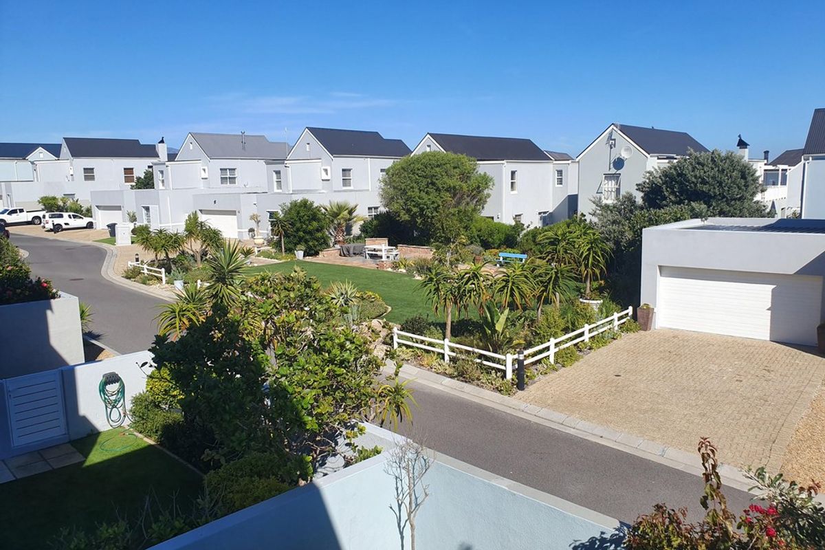 Elevated view of a residential townhouse complex featuring paved driveways, garages, and well-maintained communal garden areas.