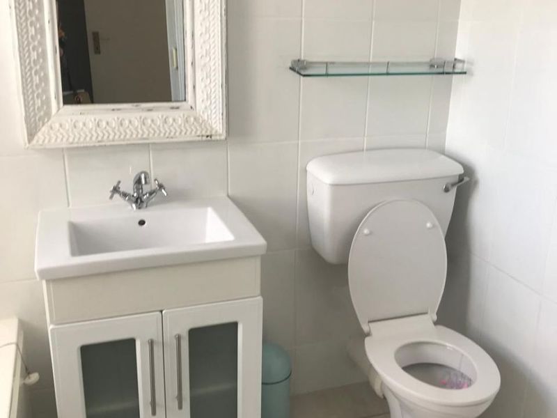 A functional bathroom featuring a white vanity cabinet with a basin, a standard toilet, and neutral wall and floor tiling.