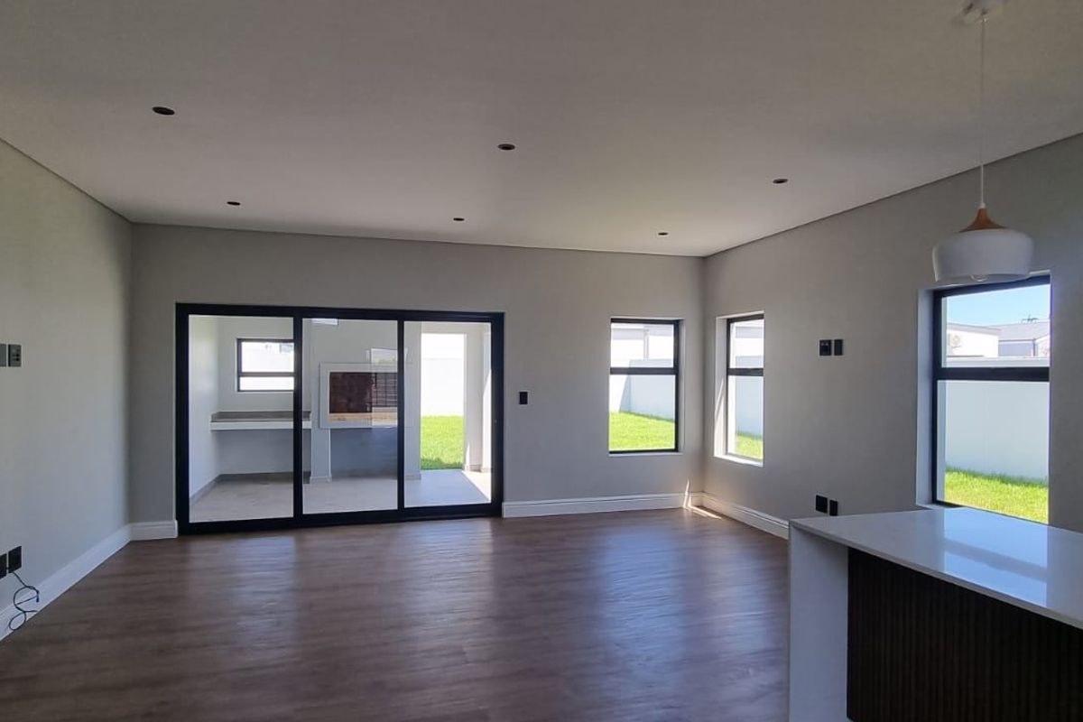 Spacious open-plan living area featuring modern finishes, recessed lighting, and large sliding doors leading to an outdoor patio space.