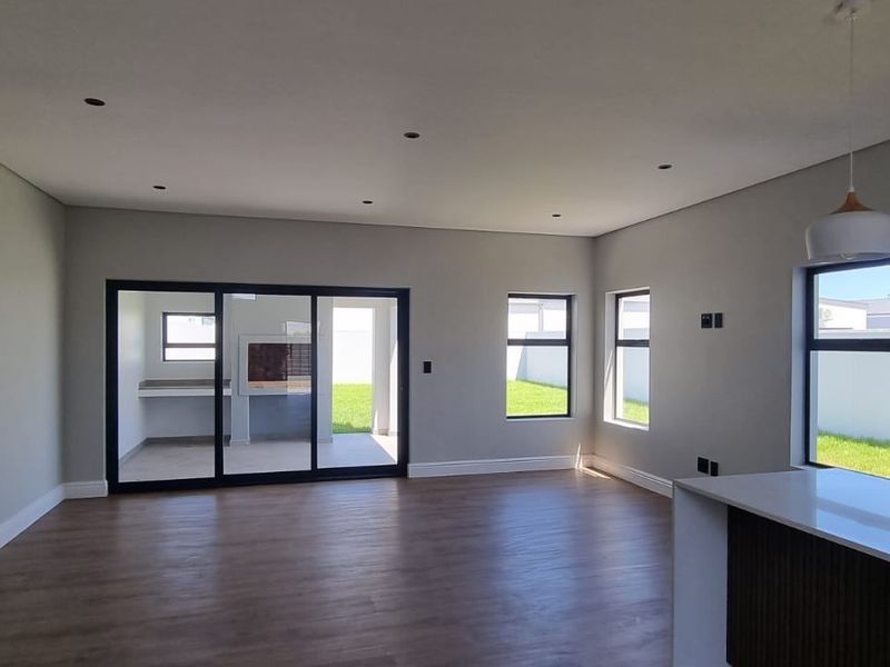 Spacious open-plan living area featuring modern finishes, recessed lighting, and large sliding doors leading to an outdoor patio space.