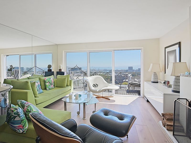 Spacious living room featuring hardwood flooring, a fireplace, and large sliding glass doors that open to a balcony with expansive city and ocean views.