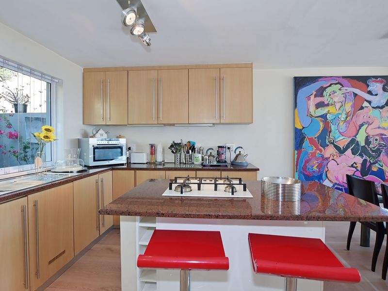 A functional kitchen featuring light wood cabinetry, granite countertops, and a central island with an integrated gas hob.