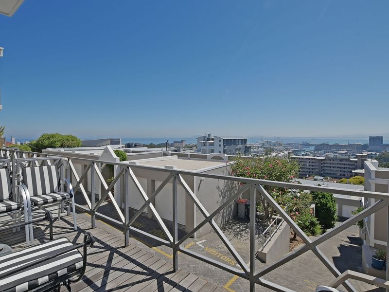 An elevated balcony featuring timber decking and a wooden balustrade, offering expansive urban and coastal views.