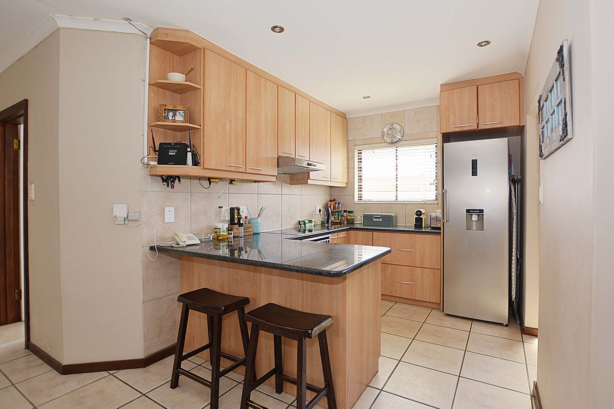Functional kitchen featuring light wood cabinetry, granite countertops, a breakfast bar, tiled flooring, and integrated space for a large refrigerator.