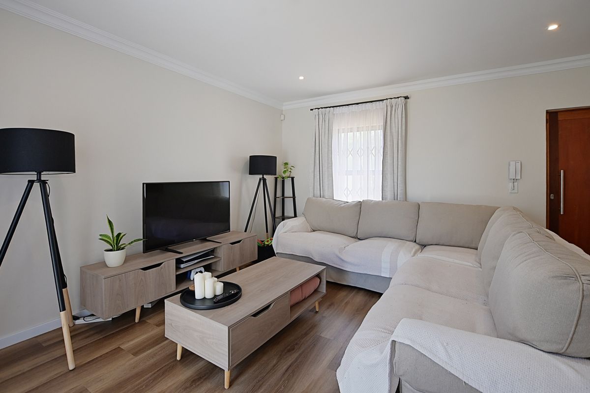 A well-maintained living room featuring neutral walls, recessed ceiling lighting, crown molding, and durable wood-look flooring.