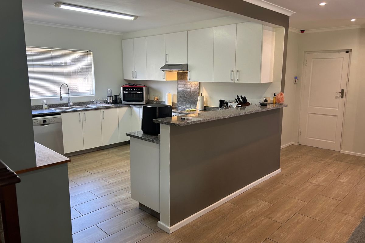 A functional kitchen featuring white cabinetry, granite countertops, a breakfast bar, and tiled flooring, offering a clean and practical layout.