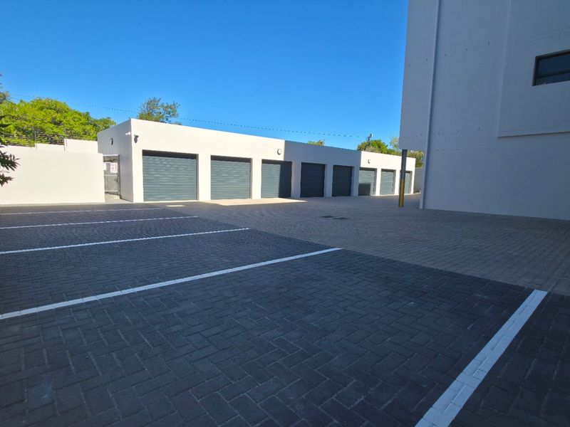 A well-maintained exterior area featuring a paved parking lot and a row of secure, individual garage units.
