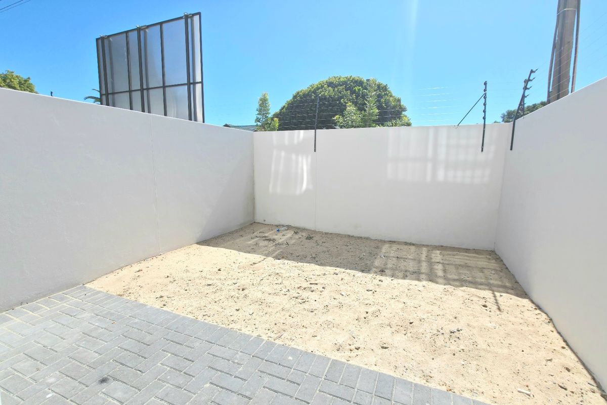 A private rear courtyard area featuring perimeter boundary walls with electric fencing and a paved section, ready for landscaping or outdoor development.