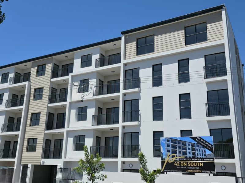 Modern multi-story apartment building facade featuring clean white finishes, dark window frames, and private balconies with metal railings.