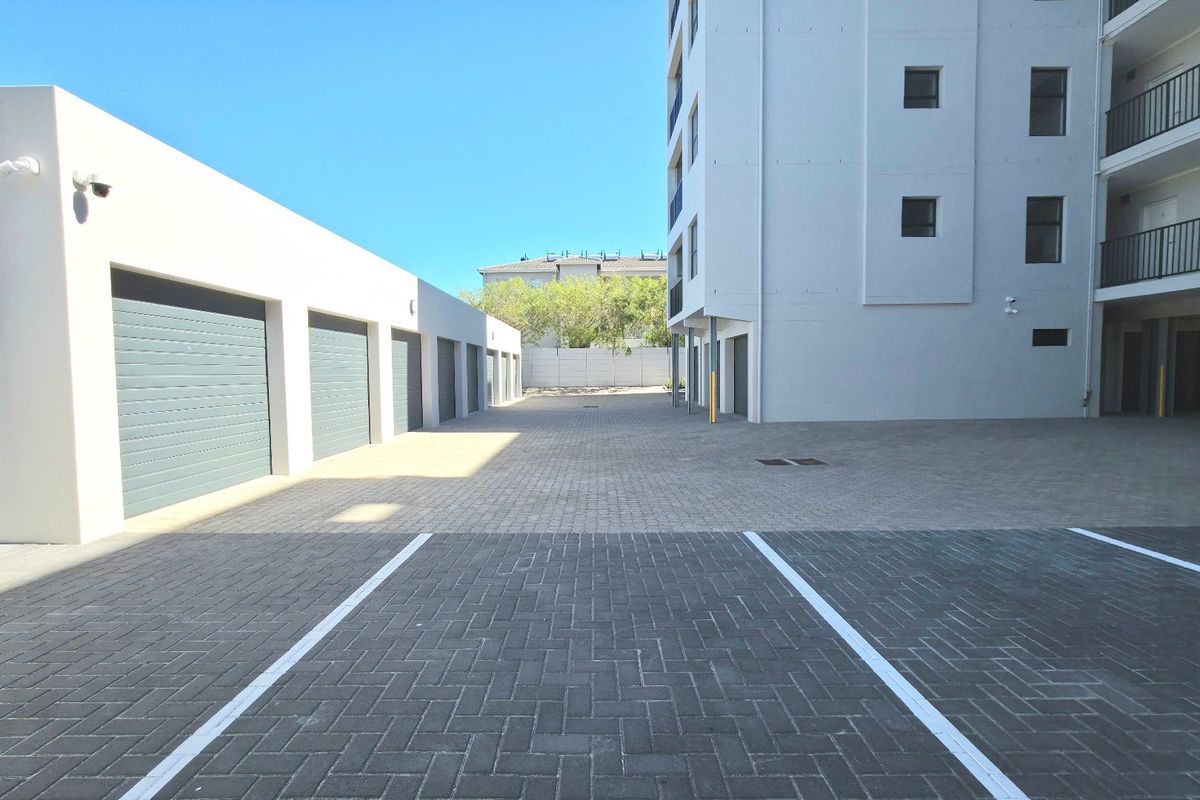 A clean, paved parking area and driveway serving the apartment complex, featuring multiple garage units and building access points.