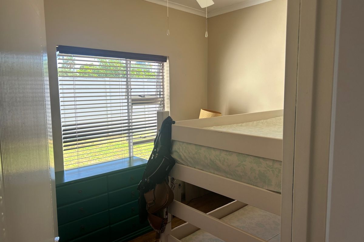 A bedroom featuring a ceiling fan and window blinds, providing natural light and ventilation.