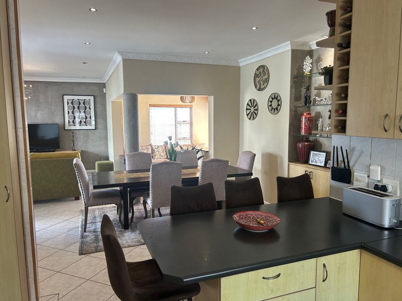 Open-plan living area featuring a kitchen with breakfast bar, dining space, and a connected lounge area with tiled flooring and recessed lighting.