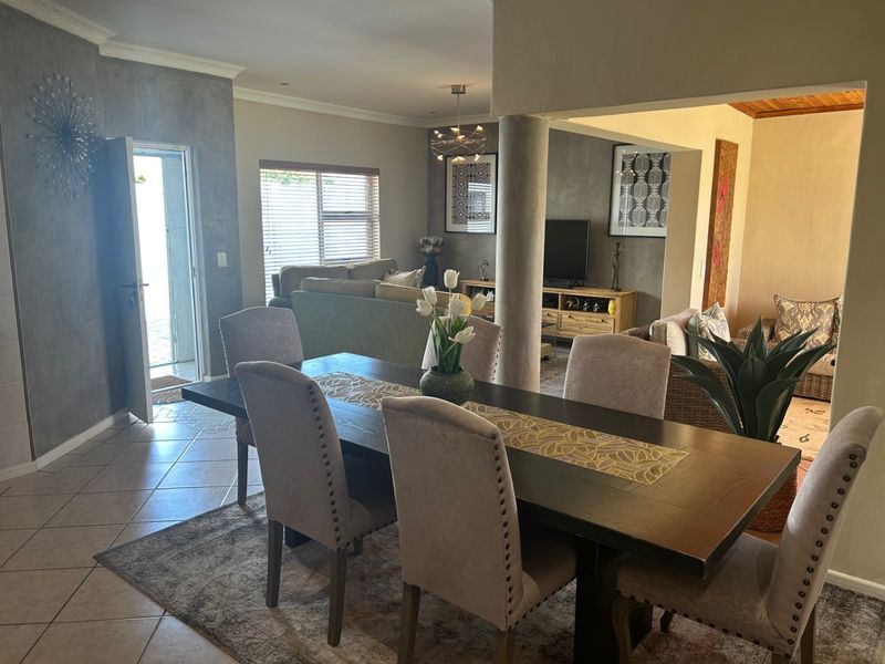 Open plan dining and living area featuring tiled flooring, a structural support column, and direct access to an outdoor patio area.