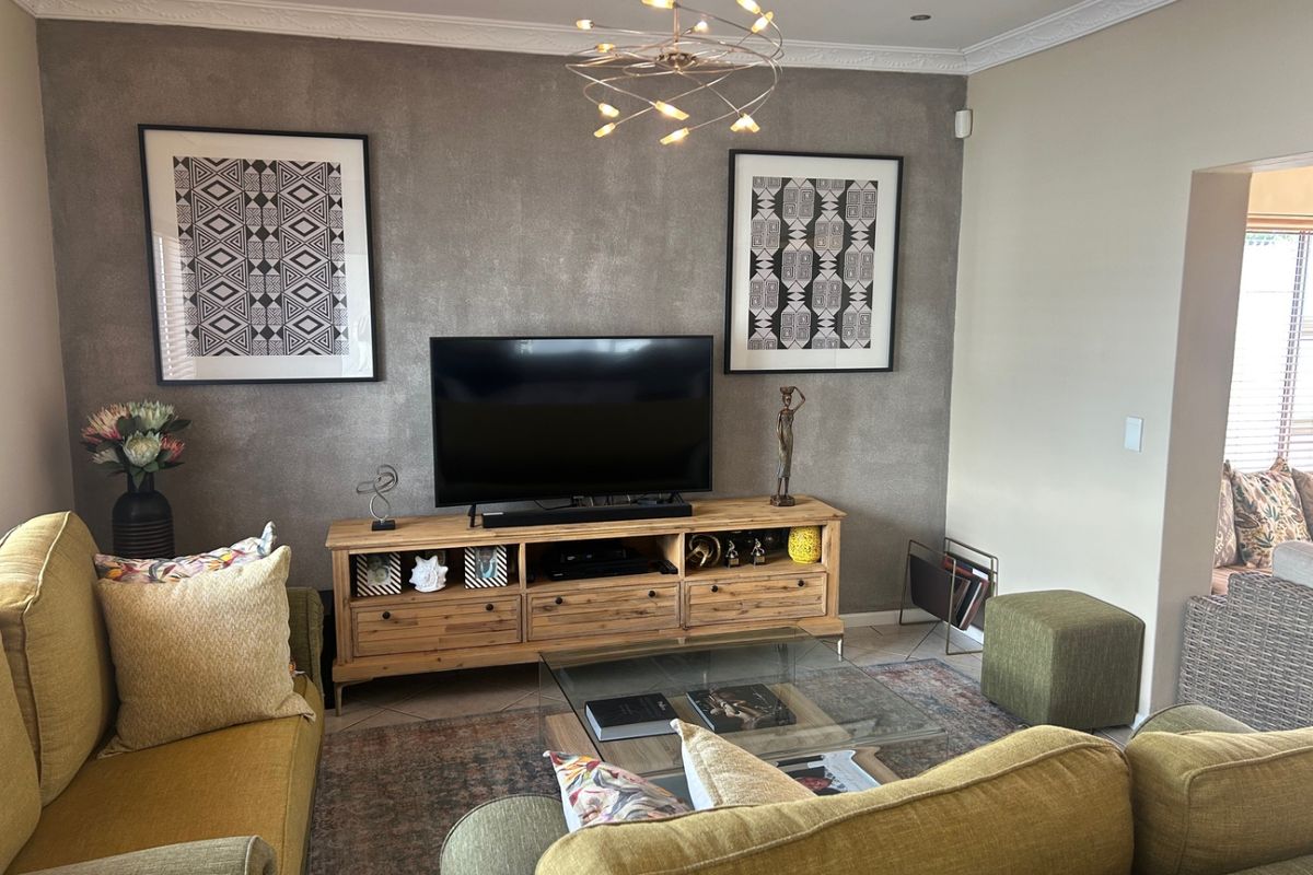 A well-maintained living room featuring a textured feature wall, decorative crown molding, and modern recessed lighting.