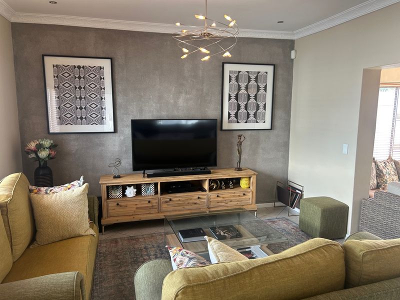 A well-maintained living room featuring a textured feature wall, decorative crown molding, and modern recessed lighting.