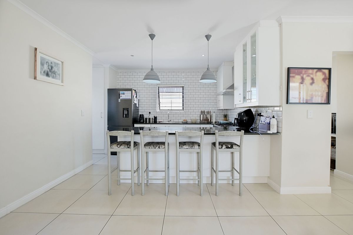 Modern kitchen featuring a breakfast bar, subway tile backsplash, sleek cabinetry, and integrated lighting, creating a clean and functional culinary space.