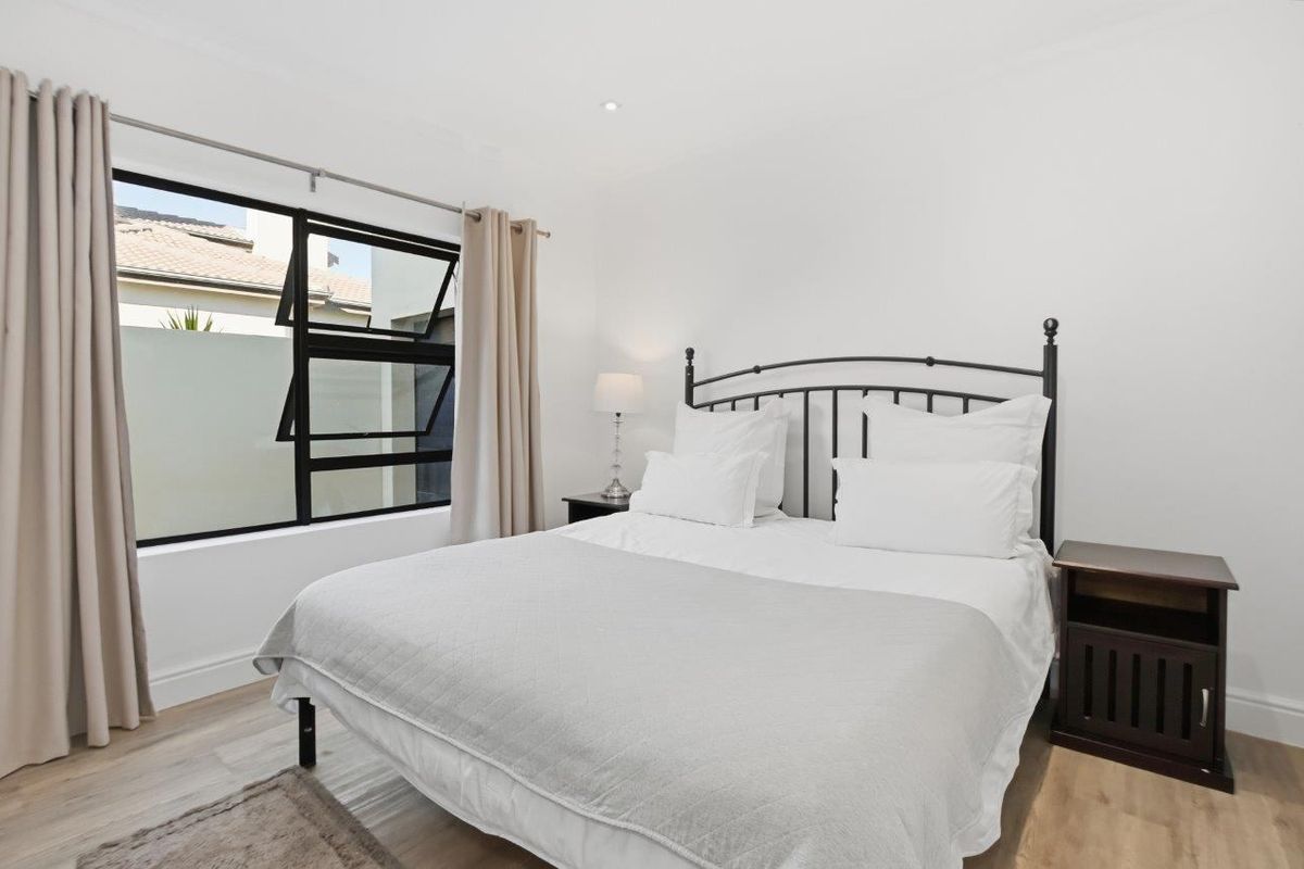 A bright and well-maintained bedroom featuring neutral tones, modern window frames, and recessed ceiling lighting.