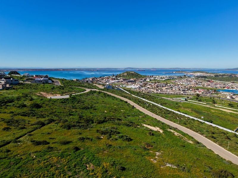 An aerial view of the vacant residential land, showcasing the surrounding coastal landscape, nearby town, and existing road infrastructure.