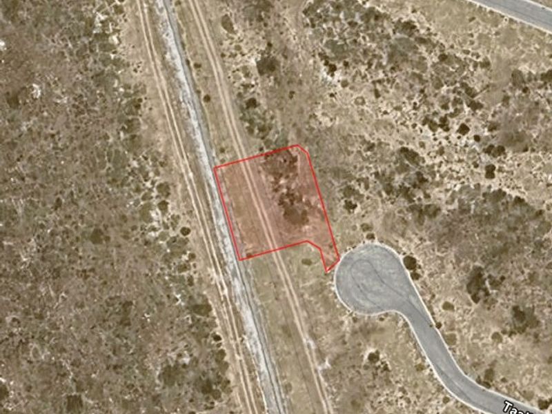Aerial satellite view of a vacant residential plot highlighted in red, showing surrounding terrain and nearby street access.