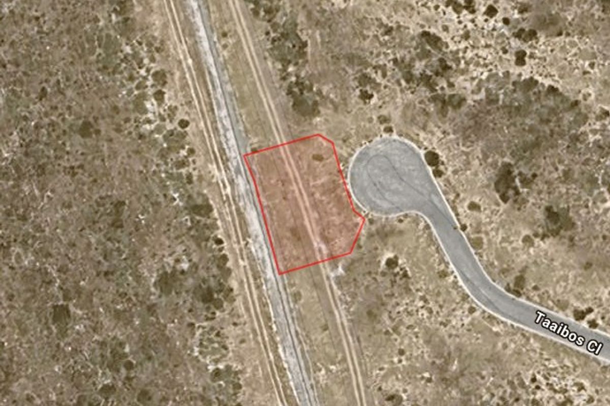 Aerial view of a vacant residential plot outlined in red, situated adjacent to a paved cul-de-sac in a natural landscape setting.