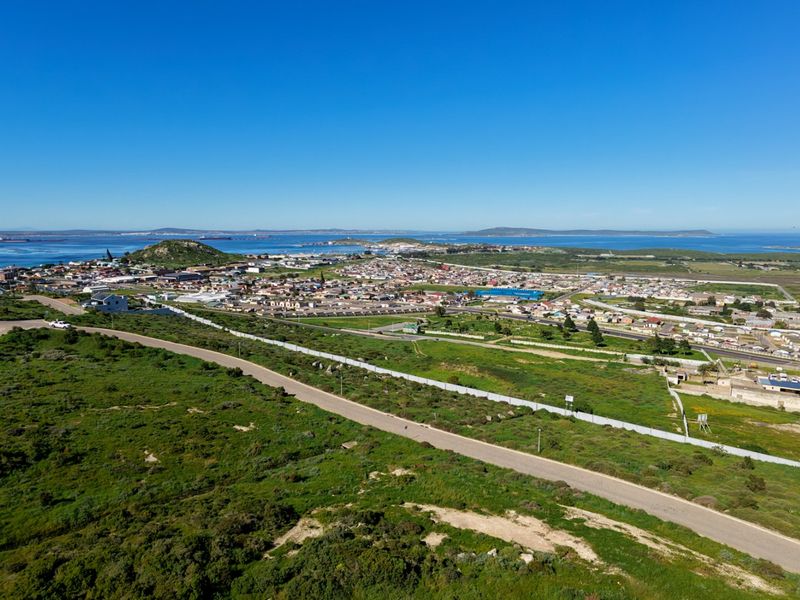 Aerial view of the vacant residential land, showcasing the surrounding landscape, nearby coastal town, and existing road infrastructure.