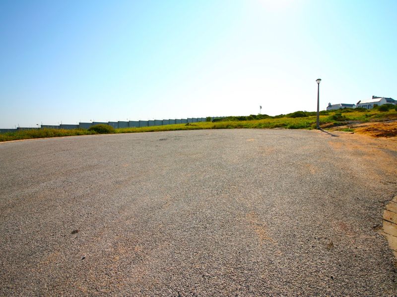 A view of a paved residential street or cul-de-sac area with a street light and surrounding natural landscape.
