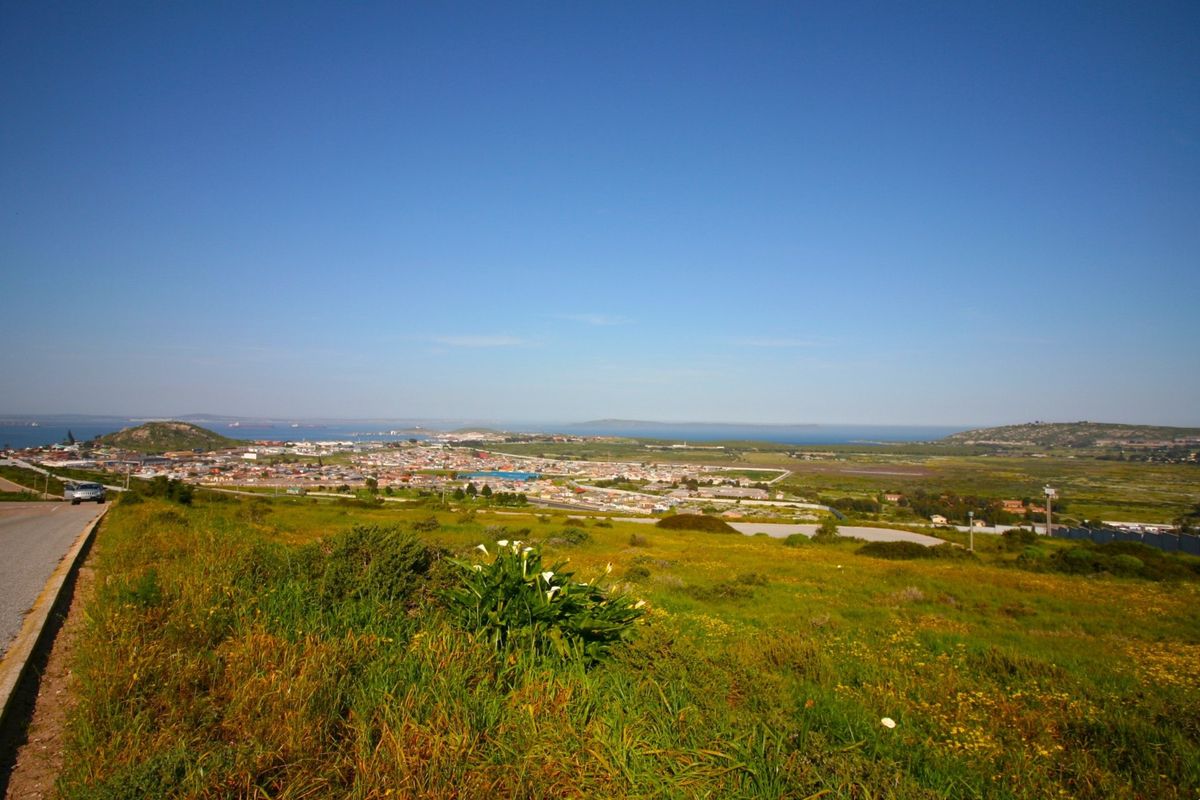 A wide-angle view overlooking the surrounding landscape, residential area, and distant coastline from the vacant land plot.