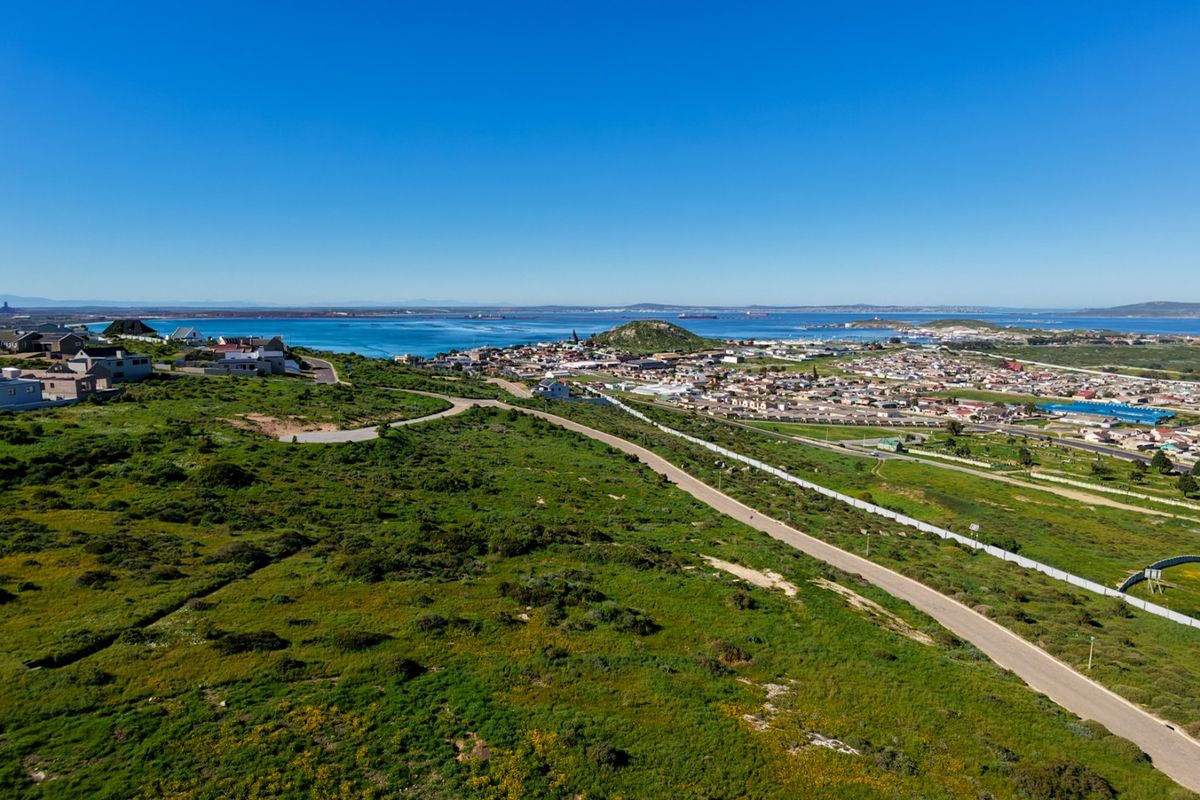 An aerial view of the vacant residential land, showcasing the surrounding coastal landscape, nearby town, and road access.