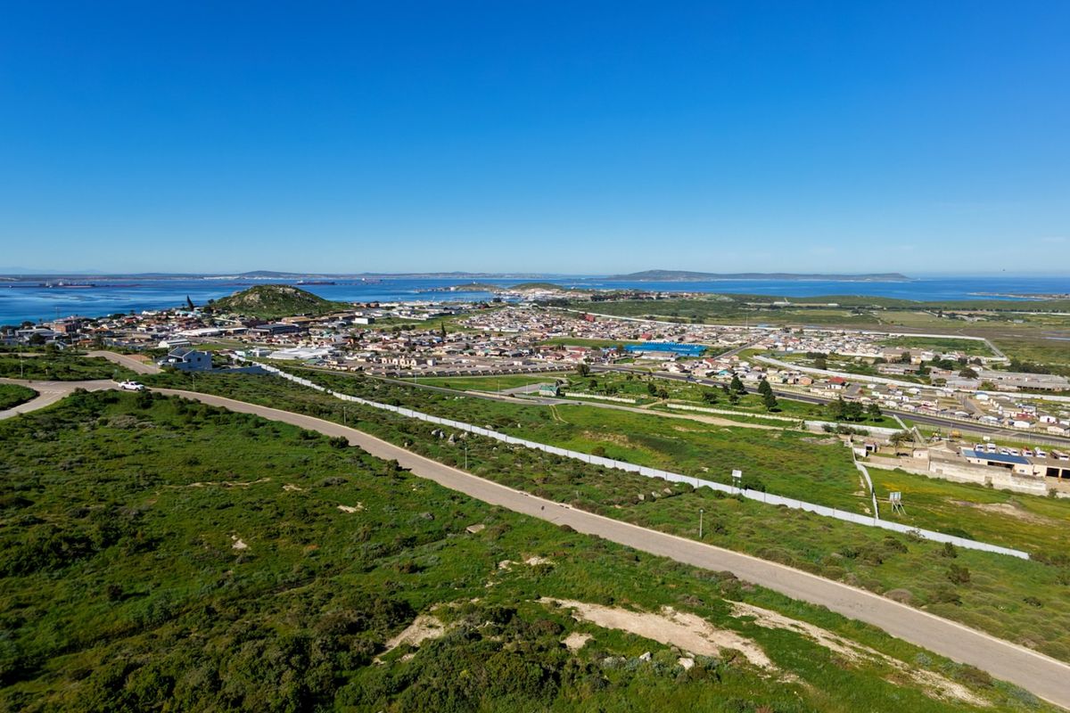 Aerial view of the vacant residential land, showcasing the surrounding landscape, nearby coastal town, and existing road infrastructure.