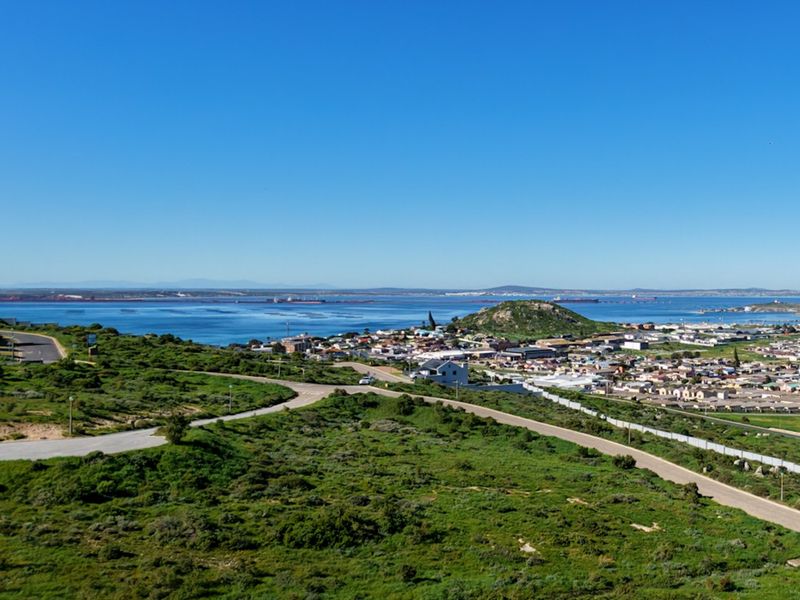 An elevated panoramic view of the coastal landscape, surrounding residential area, and nearby bay.