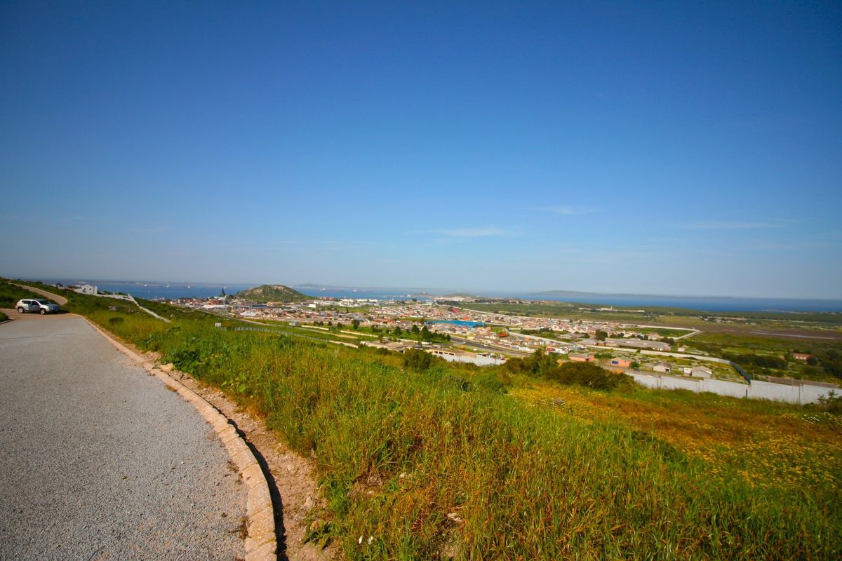 Elevated panoramic view overlooking the surrounding residential area and distant coastline from a paved access road.