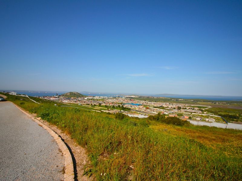 Elevated panoramic view overlooking the surrounding residential area and distant coastline from a paved access road.