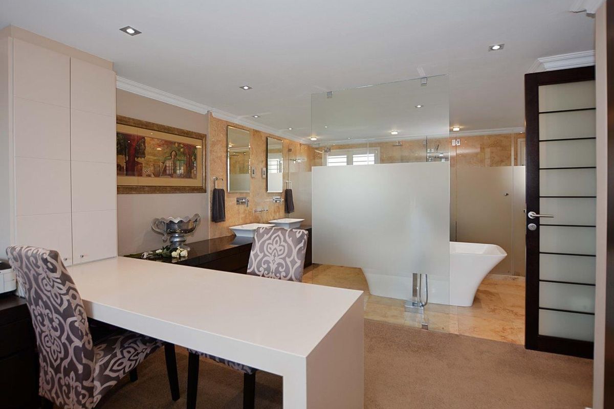 Spacious modern bathroom featuring a double vanity, freestanding bathtub, and a glass-enclosed shower area with elegant stone tiling and recessed lighting.